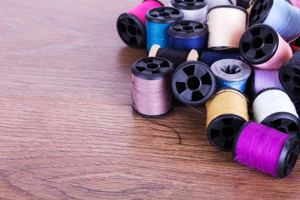 Scattered cotton reels on a wooden surface — Stock Photo, Image