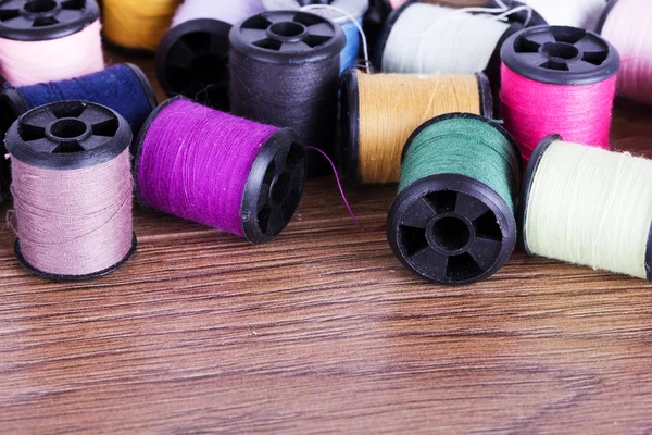 Scattered cotton reels on a wooden surface — Stock Photo, Image