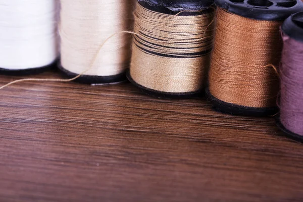 Reels of brown cotton on a wooden surface — Stock Photo, Image