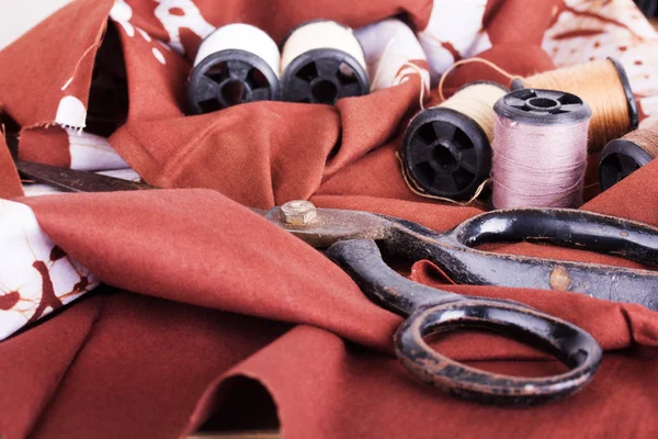 Scissors and cotton for sewing on brown material — Stock Photo, Image