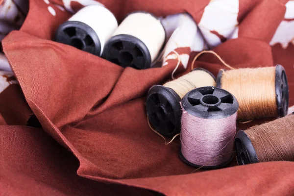 Reels of cotton for sewing on brown material — Stock Photo, Image