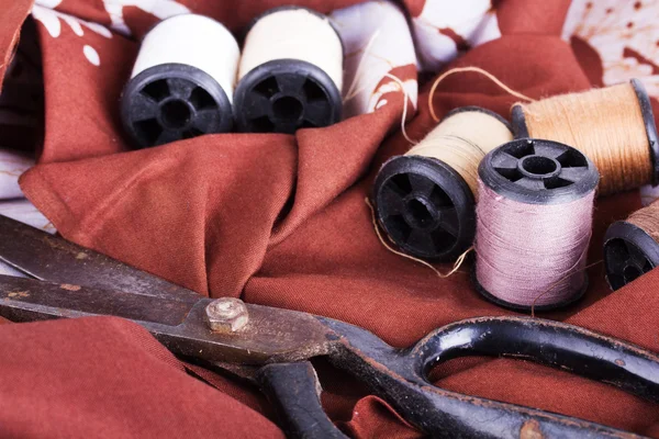 Scissors and cotton for sewing on brown material — Stock Photo, Image