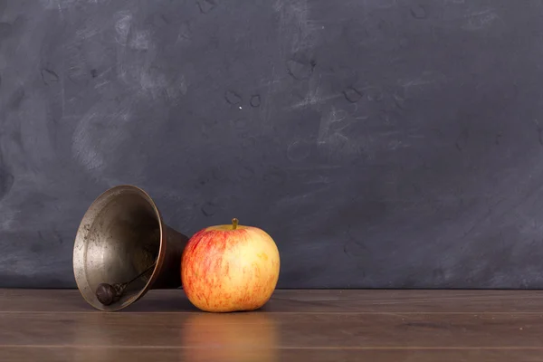Sino antiquado e maçã contra um quadro negro — Fotografia de Stock