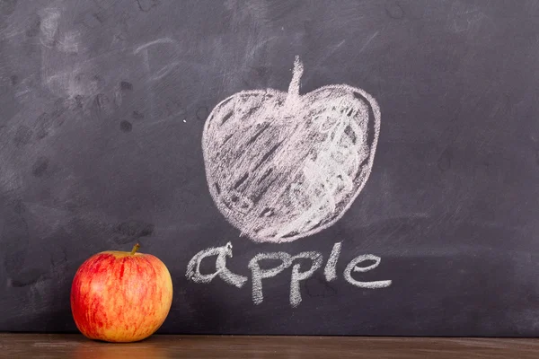 Apple op een houten oppervlak tegen een schoolbord — Stockfoto