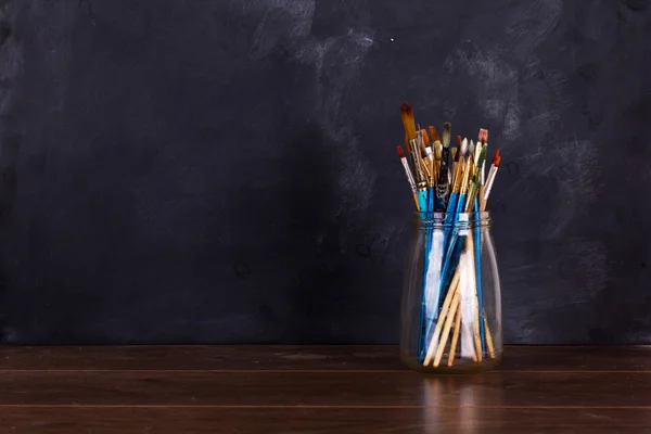 Verf penselen in een pot tegen een zwarte achtergrond — Stockfoto