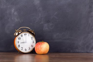 Saat ve bir elma bir kara tahta karşı