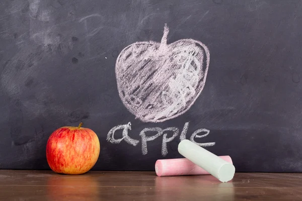 Apple op een houten oppervlak tegen een schoolbord — Stockfoto