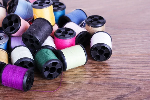 Scattered cotton reels on a wooden surface — Stock Photo, Image