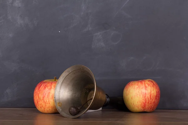 Sino antiquado e maçã contra um quadro negro — Fotografia de Stock