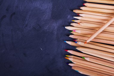 Yıpranmış siyah arka plan üzerinde renkli kalemler