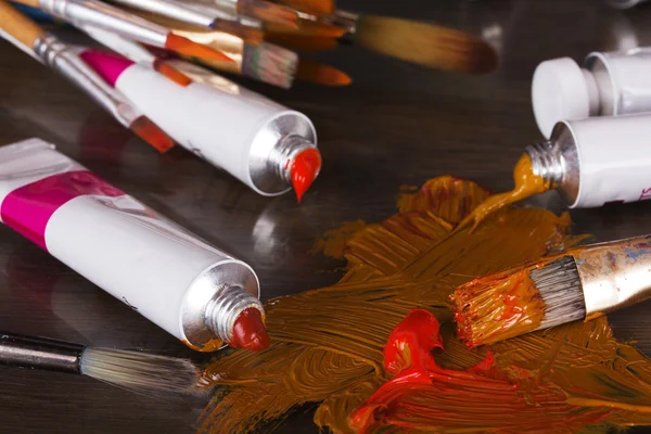 Open tubes of brown paint and brushes — Stock Photo, Image