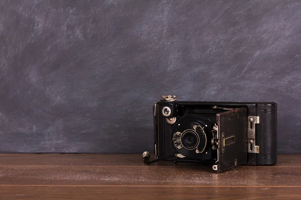 Old vintage camera against a blackboard background — Stock Photo, Image