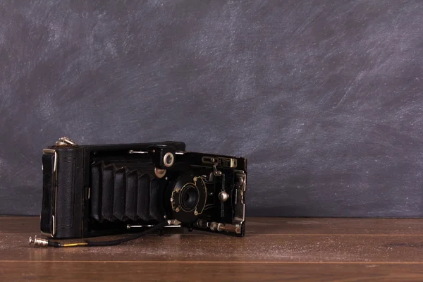 Old vintage camera against a blackboard background — Stock Photo, Image