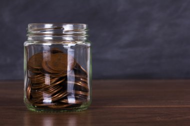 Ahşap yüzeyi eski madeni paralarla dolu cam kavanoz