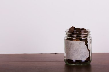 Ahşap yüzeyi eski madeni paralarla dolu cam kavanoz