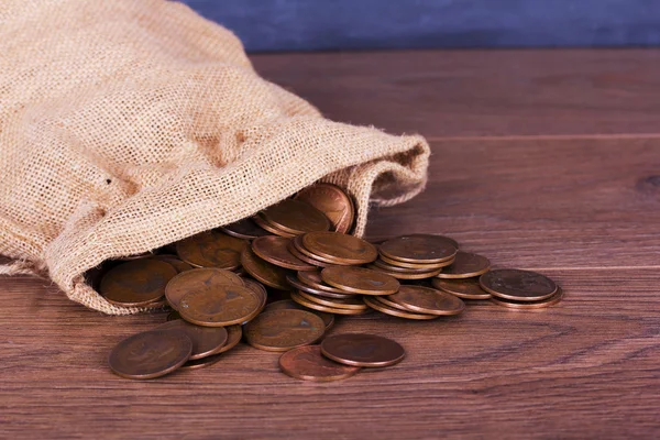 Bag of coins spilt over a wooden surface Stock Image