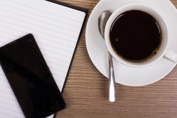 Notebook és kávé csésze fafelületre — Stock Fotó