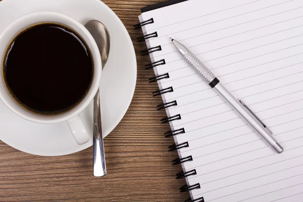 Cup of black coffee and notebook on wooden surface — Stock Photo, Image