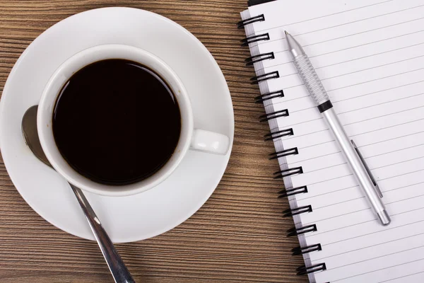 Cup of black coffee and notebook on wooden surface — Stock Photo, Image