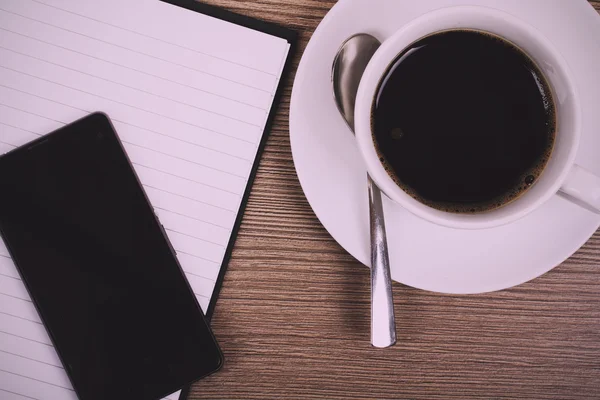 Notebook and coffee cup on a wooden surface Vintage Retro Filter — Stock Photo, Image