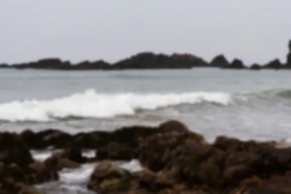 Fale po skałach na plaży nieostry. — Zdjęcie stockowe