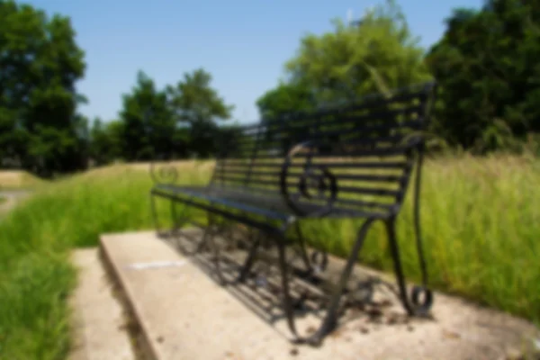 Black park bench on a concrete base  Out of focus. — Stock Photo, Image