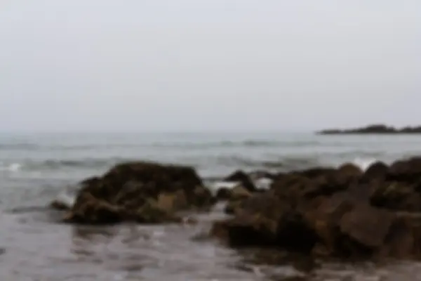 Olas sobre las rocas en la playa fuera de foco . — Foto de Stock