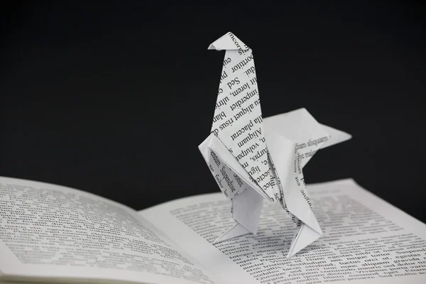 Origami dinosaur coming out van een boek — Stockfoto