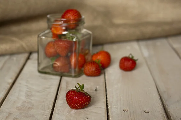 Fresas en un frasco y derramadas en la mesa —  Fotos de Stock