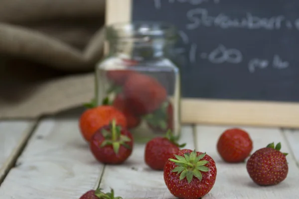 Stawberries in een kruik en gemorste op tabel — Stockfoto