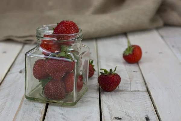 Fresas en un frasco y derramadas en la mesa — Foto de Stock