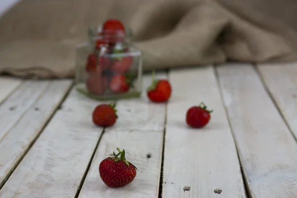 Fresas en un frasco y derramadas en la mesa —  Fotos de Stock