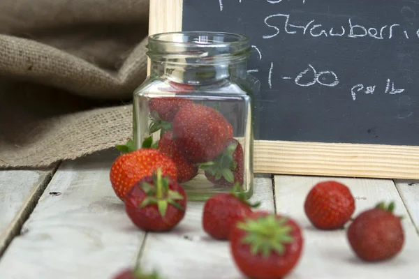 Stawberries in een kruik en gemorste op tabel — Stockfoto