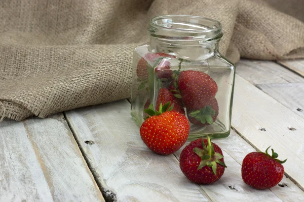 Stawberries in een kruik en gemorste op tabel — Stockfoto