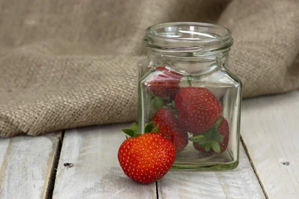 Stawberries i en burk och spilld på bord — Stockfoto