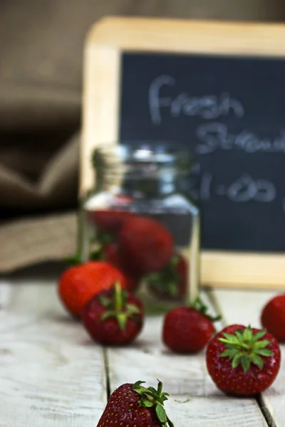 Stawberries in een kruik en gemorste op tabel — Stockfoto