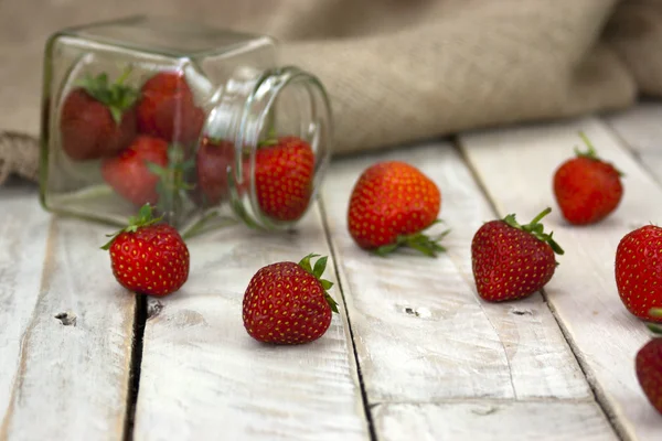 Stawberries i en burk och spilld på bord — Stockfoto