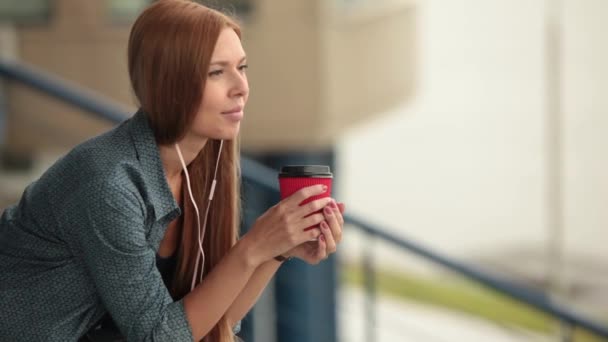 Jeune belle jolie fille assise dans la rue avec une tasse de café . — Video