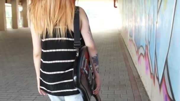 Fille avec guitare électrique marchant le long du mur de graffiti . — Video