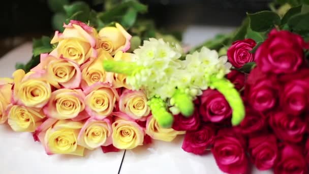 Las manos de las mujeres se ponen un ramo de rosas rojas en la tienda . — Vídeo de stock