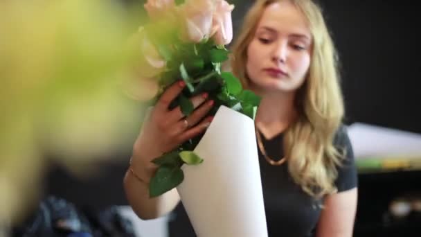 Flicka gör förpackningar för rosor i blomsteraffär. — Stockvideo