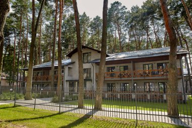 Yeşil çimleri ve fenerleri olan iki katlı küçük bir otelin cephesi..