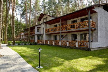 Yeşil çimleri ve fenerleri olan iki katlı küçük bir otelin cephesi..