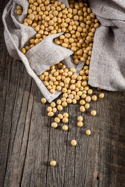 Close-up of soybean on wood background in jute sack. — Stock Photo, Image