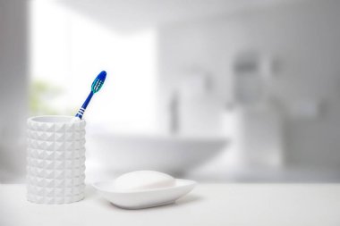 Bardaktaki diş fırçası ve masadaki sabun kabında sabun.