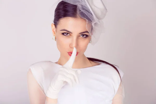 Bride retro styled shh woman wide eyed asking for silence secrecy with finger on lips hush hand gesture white