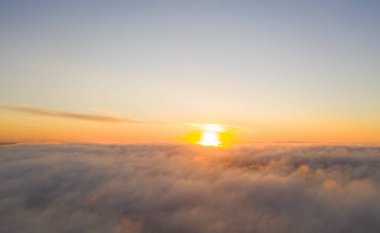 Mavi gökyüzündeki bulutların üzerinde gökyüzü manzaralı altın güneş doğumu. Üst hava manzarası bulutlu. Bulutların dokusu. Yukarıdan bak. Portakal rengi gün doğumu ya da bulutların üzerinde gün batımı. Panorama Bulutları dokusu