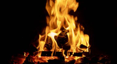 Odunla dolu sıcak bir şömine. Yanan kütüklerin doku arka planından gerçek alevler. Şömine arka planı. Ateş yakın..