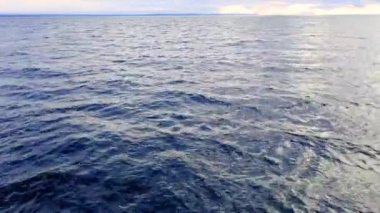 Mavi deniz suyu arka planının ve güneş yansımalarının havadan görüntüsü. Uçan İHA görüntüsü. Dalgalar su yüzeyinde. Okyanus üzerinden uçmak. Havadan okyanus manzaralı. Denizin üstünde uç.