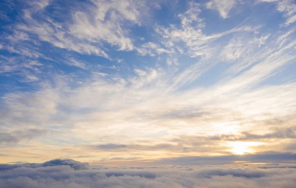 Aerial view gold sunrise over clouds in blue sky. Aerial top view cloudscape. Texture of clouds. View from above. Orange sunrise or sunset over clouds. Panorama clouds texture